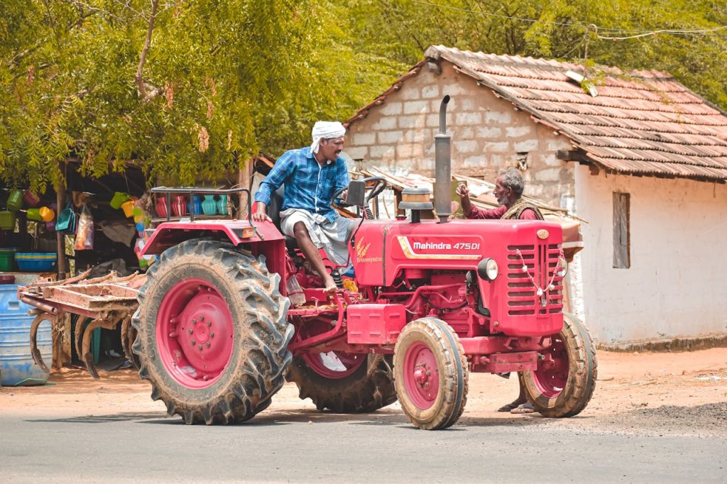 A farmer driving a red Mahindra tractor in Aranthangi, Tamil Nadu, India, showcasing rural life.