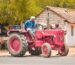 A farmer driving a red Mahindra tractor in Aranthangi, Tamil Nadu, India, showcasing rural life.